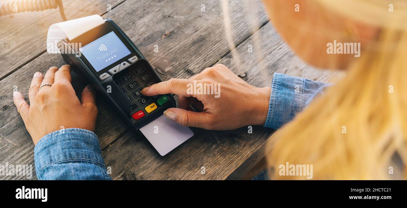 Woman hand enters PIN code on payment terminal in a restaurant Stock Photo