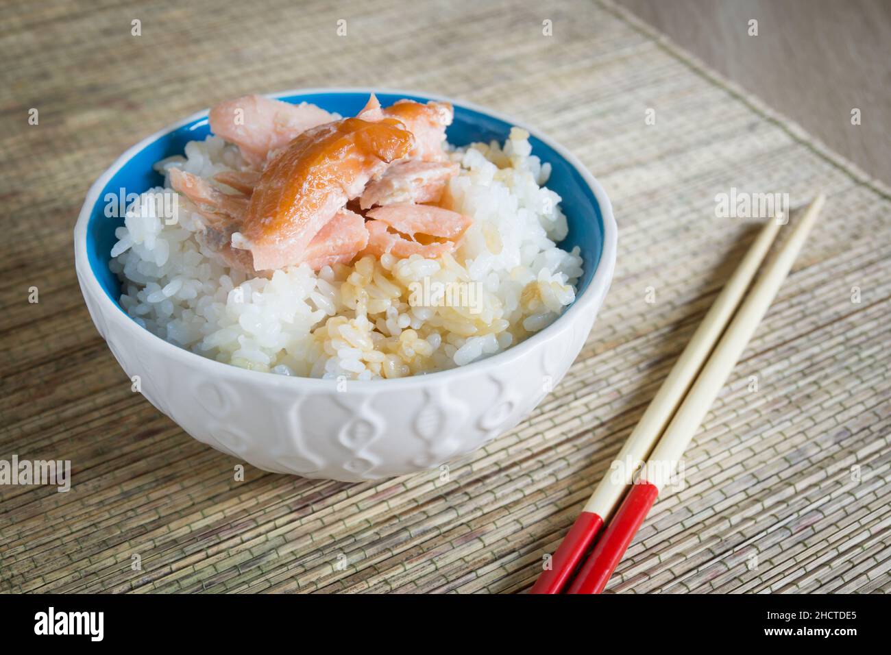 Japanese uruchi mai steamed rice with smoked salmon flakes and soy sauce in a pretty ceramic bowl with chopsticks Stock Photo