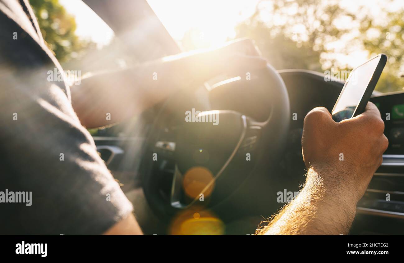 Close-up of young man holding mobile phone in his hand he using navigator during driving Stock Photo