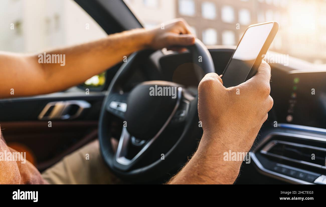 Man looking at mobile phone while driving a car Stock Photo
