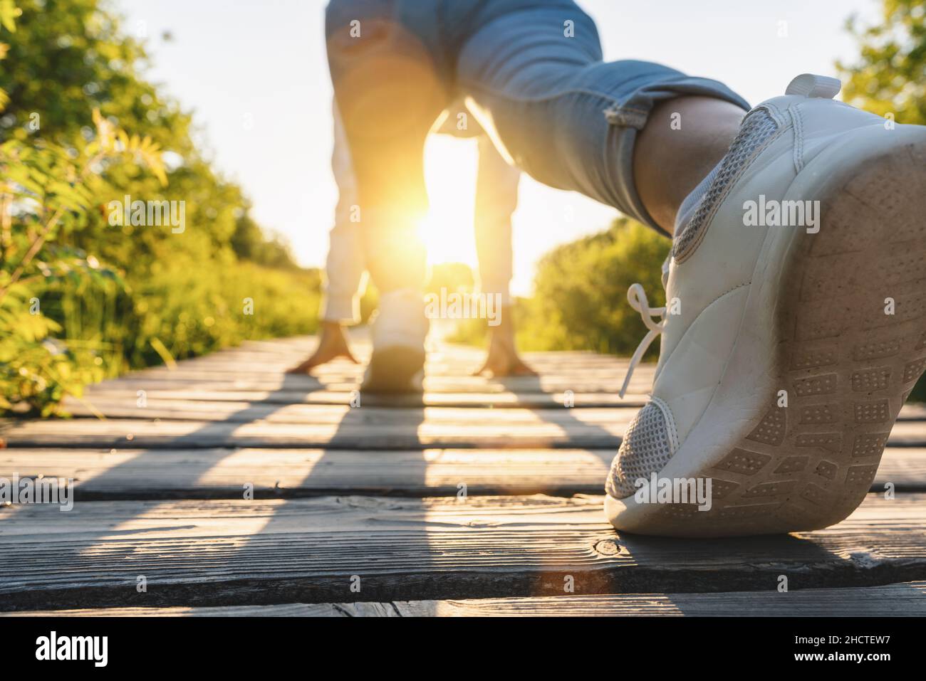 young woman starts to running at a boardwalk at sunset, runner sport athlete concept image Stock Photo