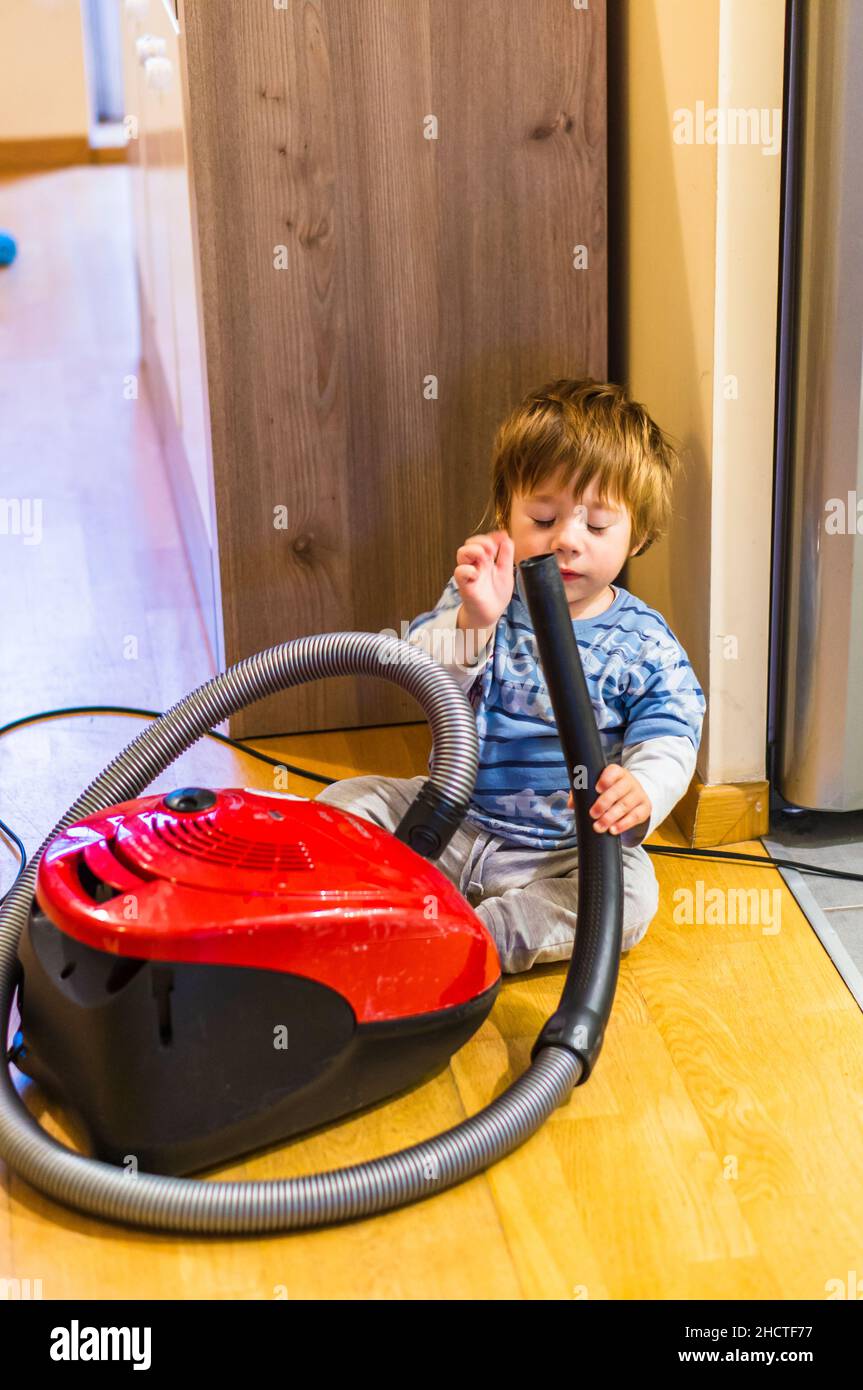 Young Polish boy playing with a Bosch brand vacuum cleaner on the floor