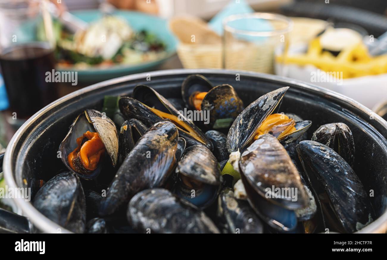 Mussels in a bowl with French fries on a restaurant.  A classic dish in Belgium, France and Netherlands. Stock Photo