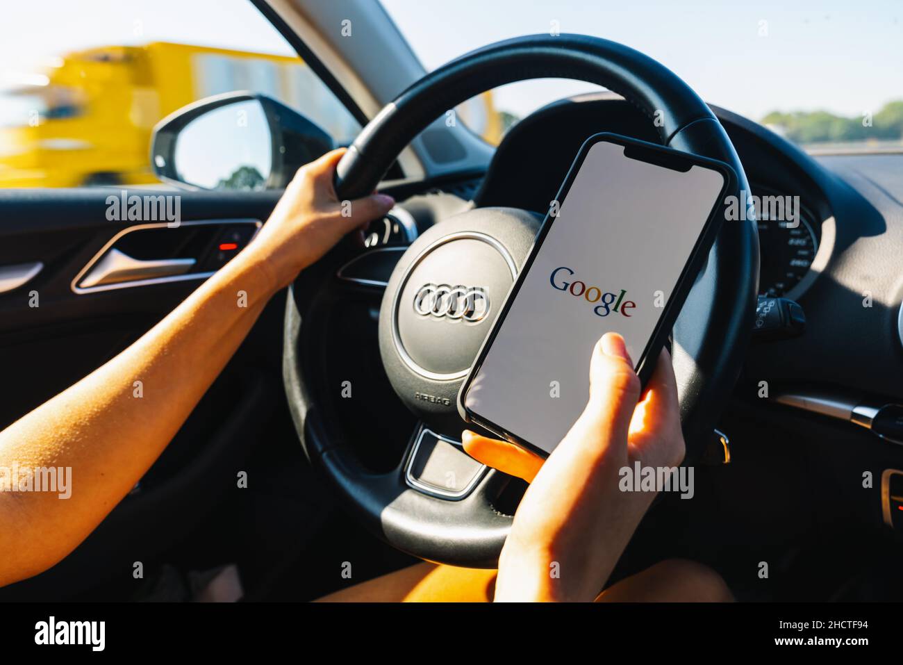 Woman hand holding iphone Xs with logo of google in a car. Google is an American technology and online services company Stock Photo