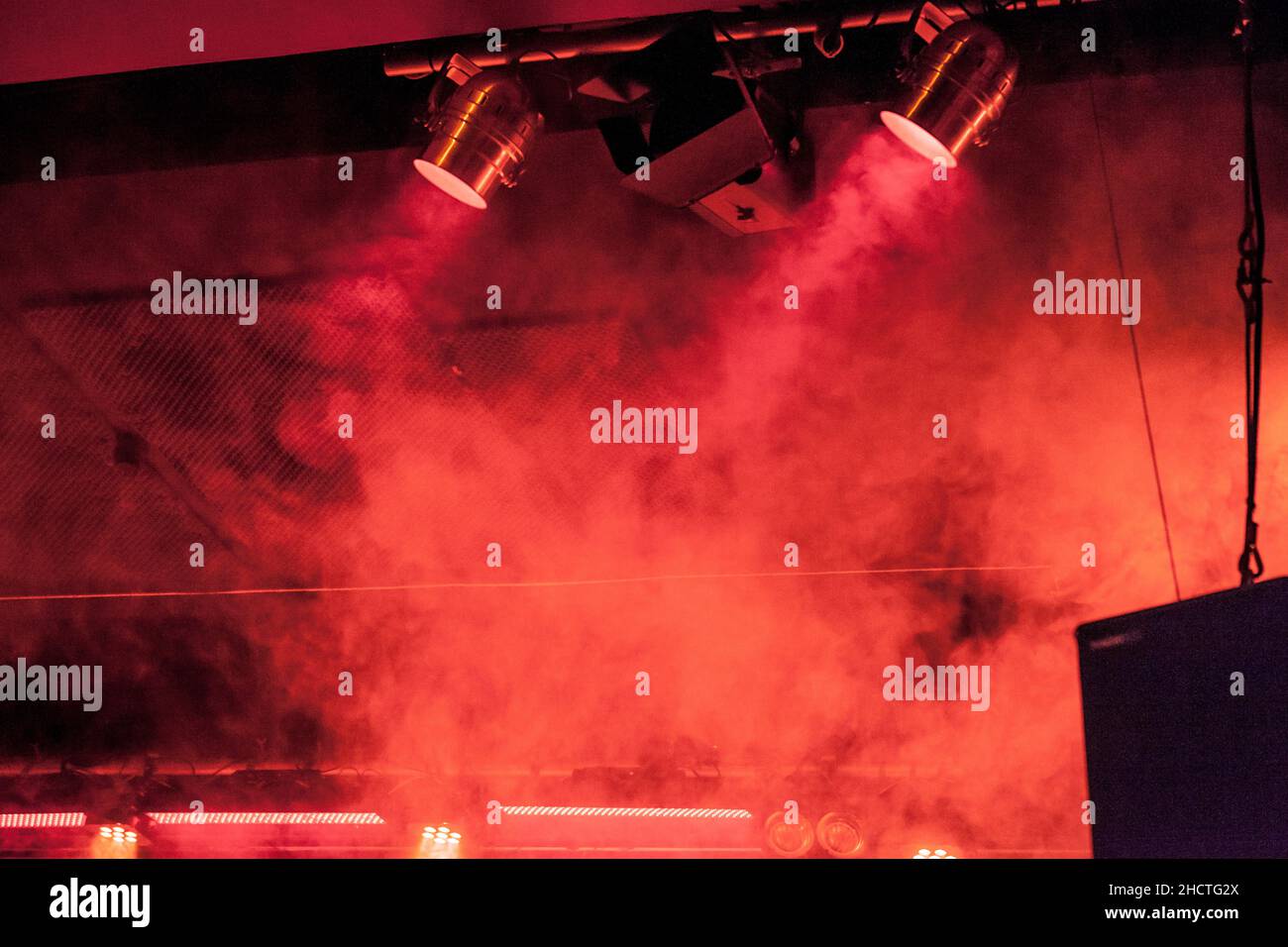 Stage spots illuminates red haze at live performance. Warm ambience Stock Photo