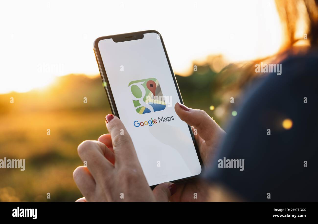 Hand Holding Smartphone with Google Maps application o. Google Maps is a service that provides information about geographical regions and sites around Stock Photo