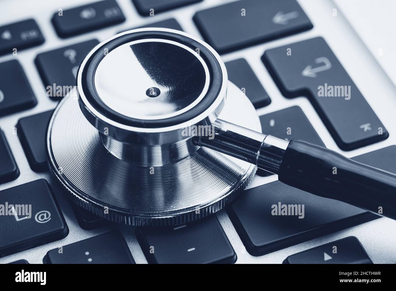 Silver stethoscope lying down on an notebook, blue toned Stock Photo
