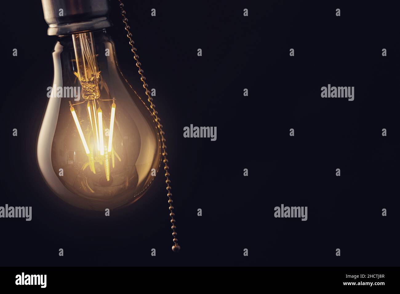 Vintage hanging light bulb with switch over dark background Stock Photo