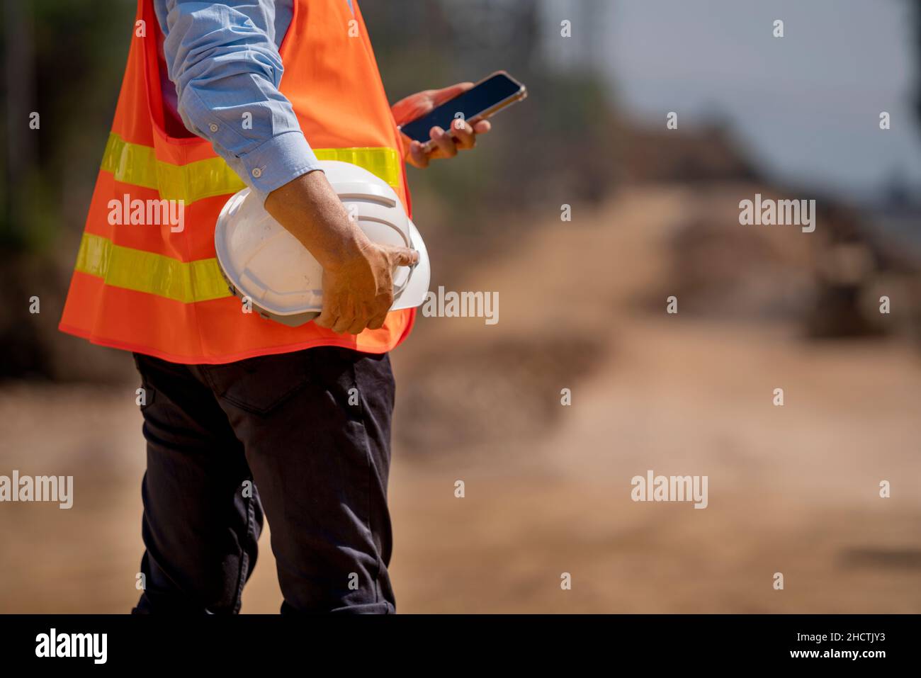Man holding White helmet close up. Construction workers working on construction site.  Back side view Stock Photo
