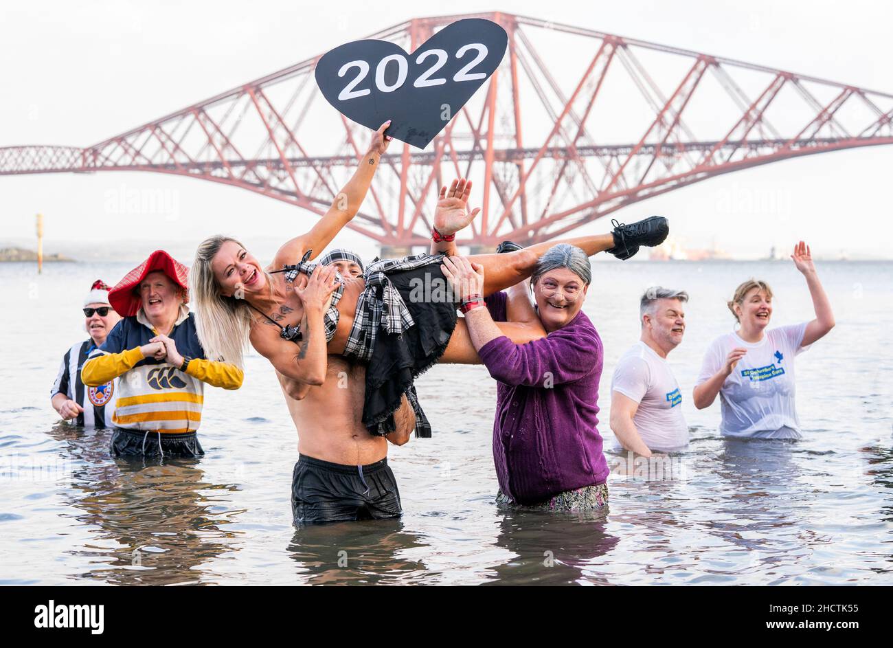 People take part in a New Year's Day dip in front of the Forth Bridge ...