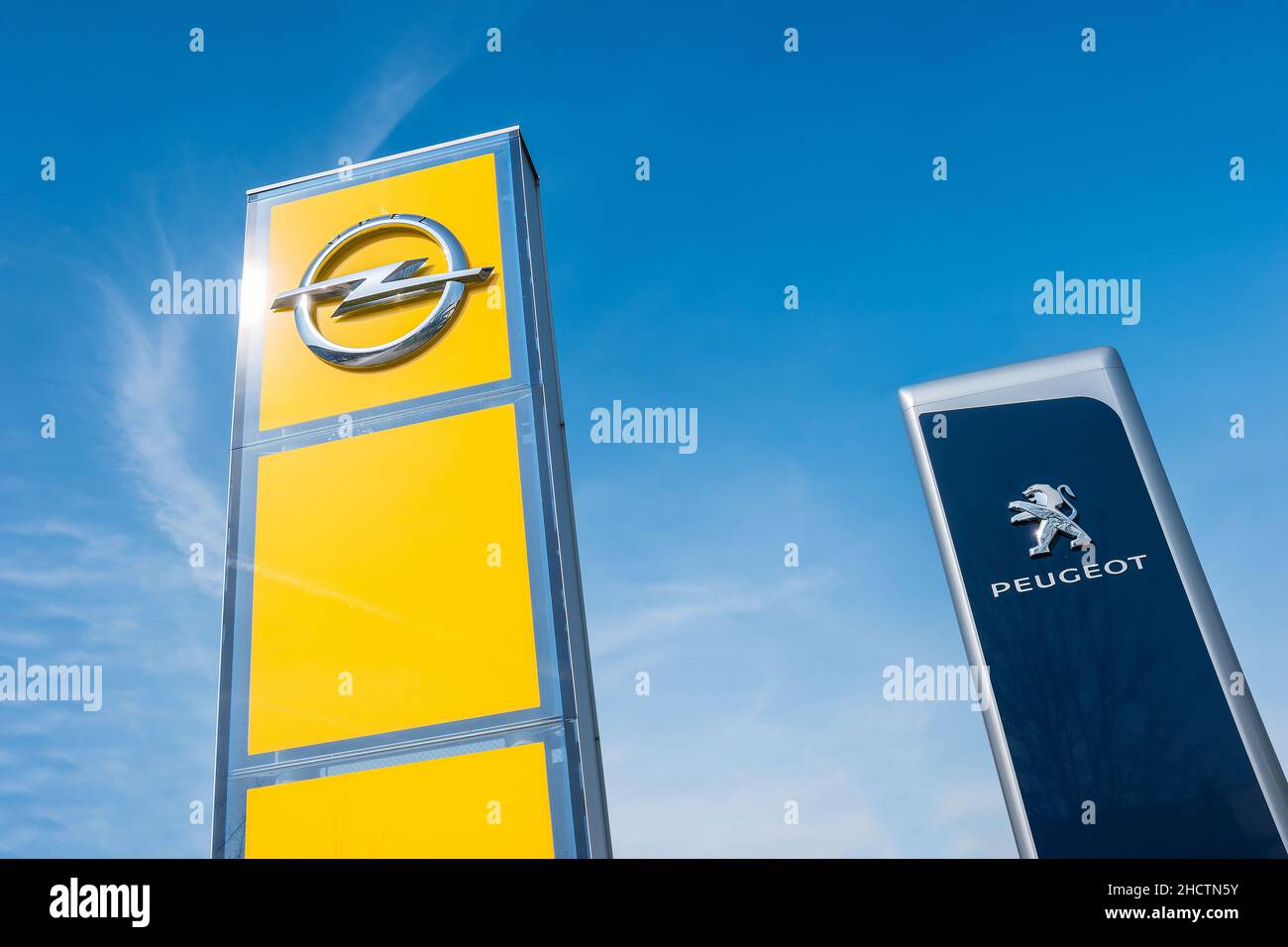 Peugeot and Opel dealership sign against blue sky. Peugeot is a French automobile manufacturer and part of Groupe PSA. Opel AG is a German automobile Stock Photo