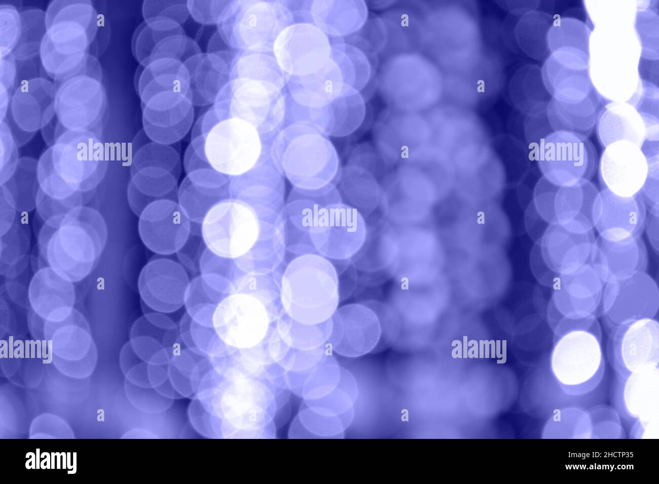Blurred lights Very Peri color. Lighted garland, bokeh festive background. Copy space. Stock Photo