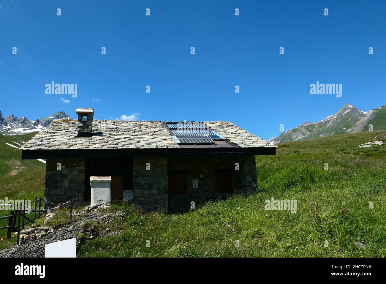 Roof of a house equipped with photovoltaic panels. Dwelling in nature with the mountain in the background blurred voluntarily. Stock Photo