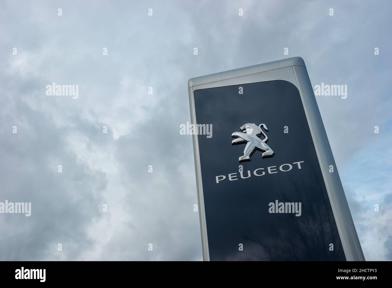 Peugeot dealership sign against cloudy sky. Peugeot is a French automobile manufacturer and part of Groupe PSA. Stock Photo