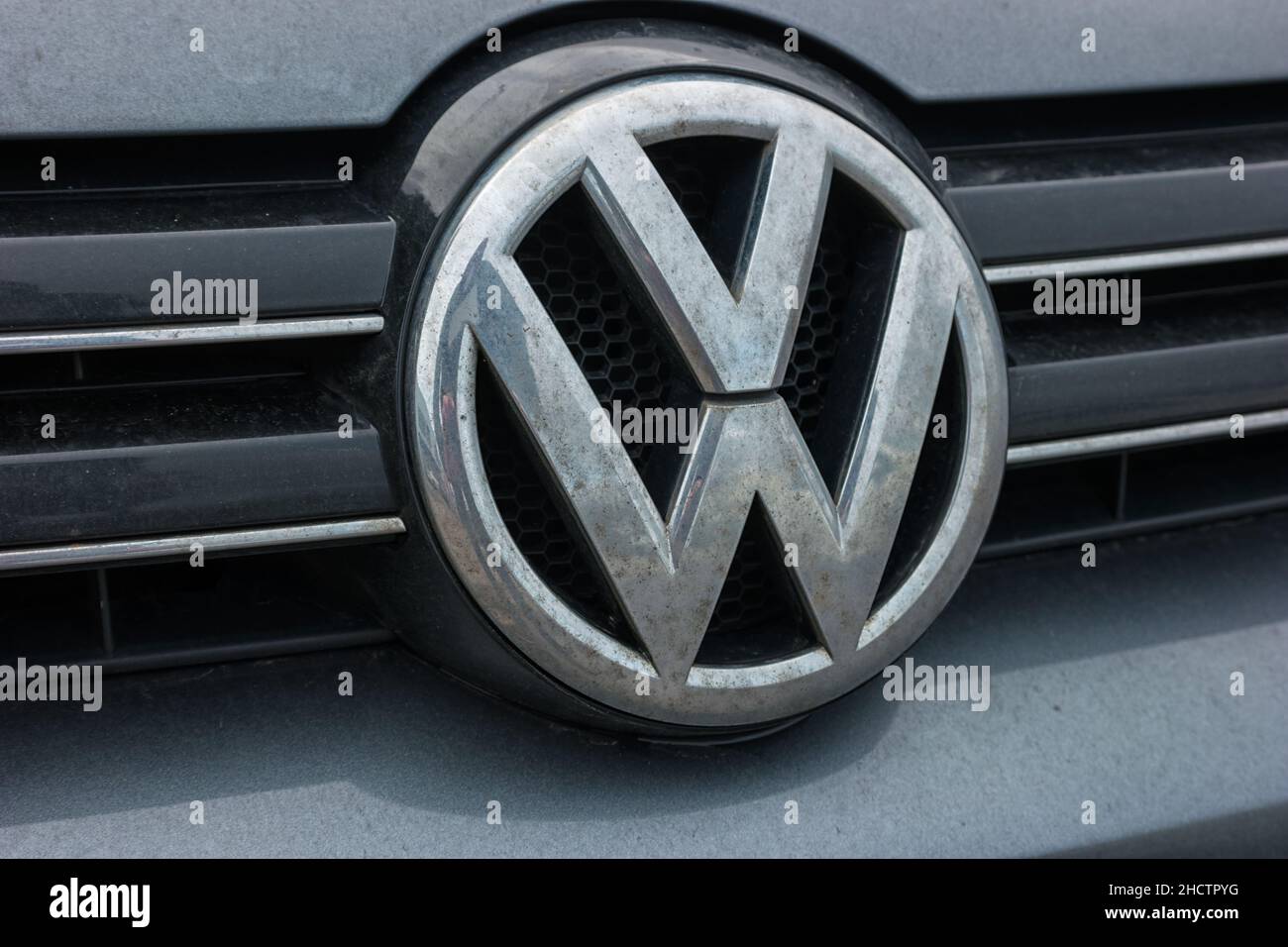 Dirty Volkswagen VW plate logo on a car grilll. Volkswagen is a famous European car manufacturer company based on Germany. Stock Photo
