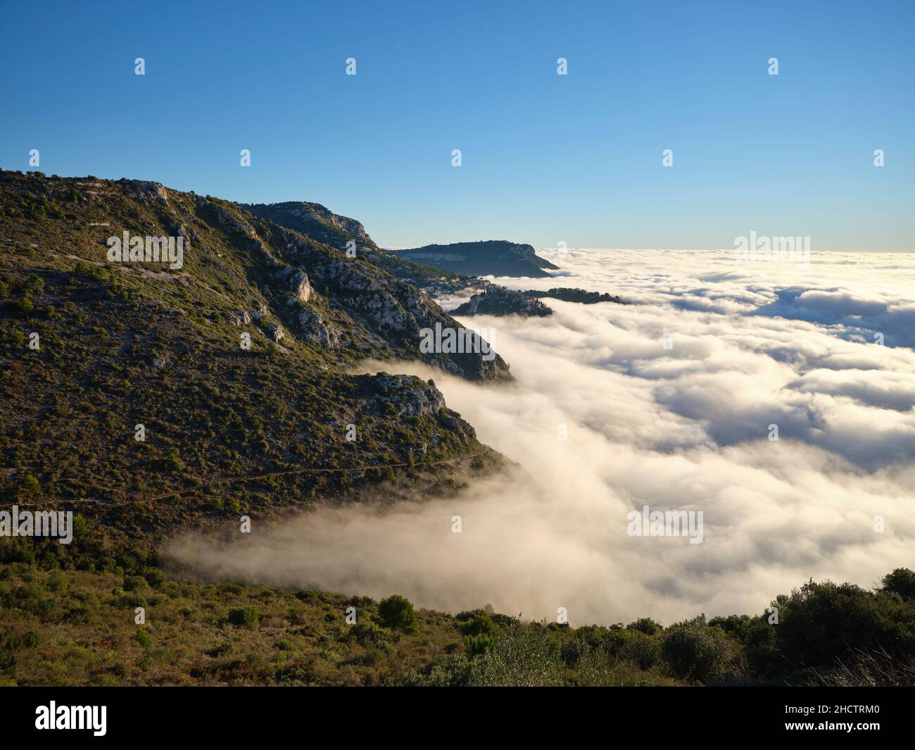 The mountainous landscape of the French Riviera overlooking a sea of clouds above the Mediterranean Sea; a very rare occurence. Èze-Village, France. Stock Photo