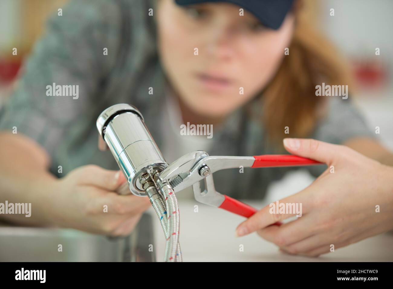 female plumber fixing a kitchen sink Stock Photo