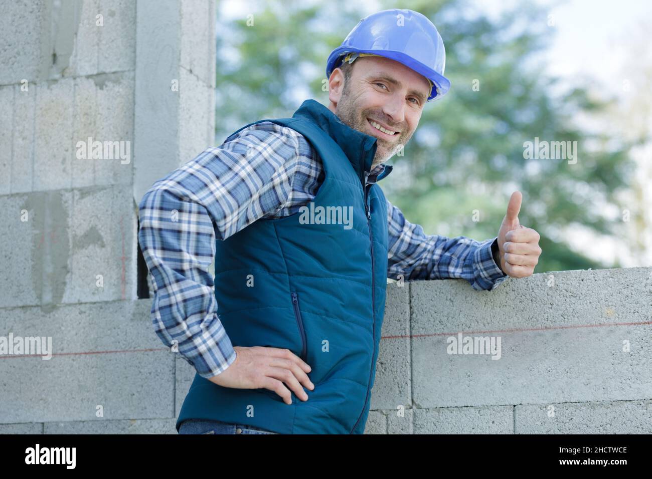 optimistic worker builder man posing showing thumb up Stock Photo