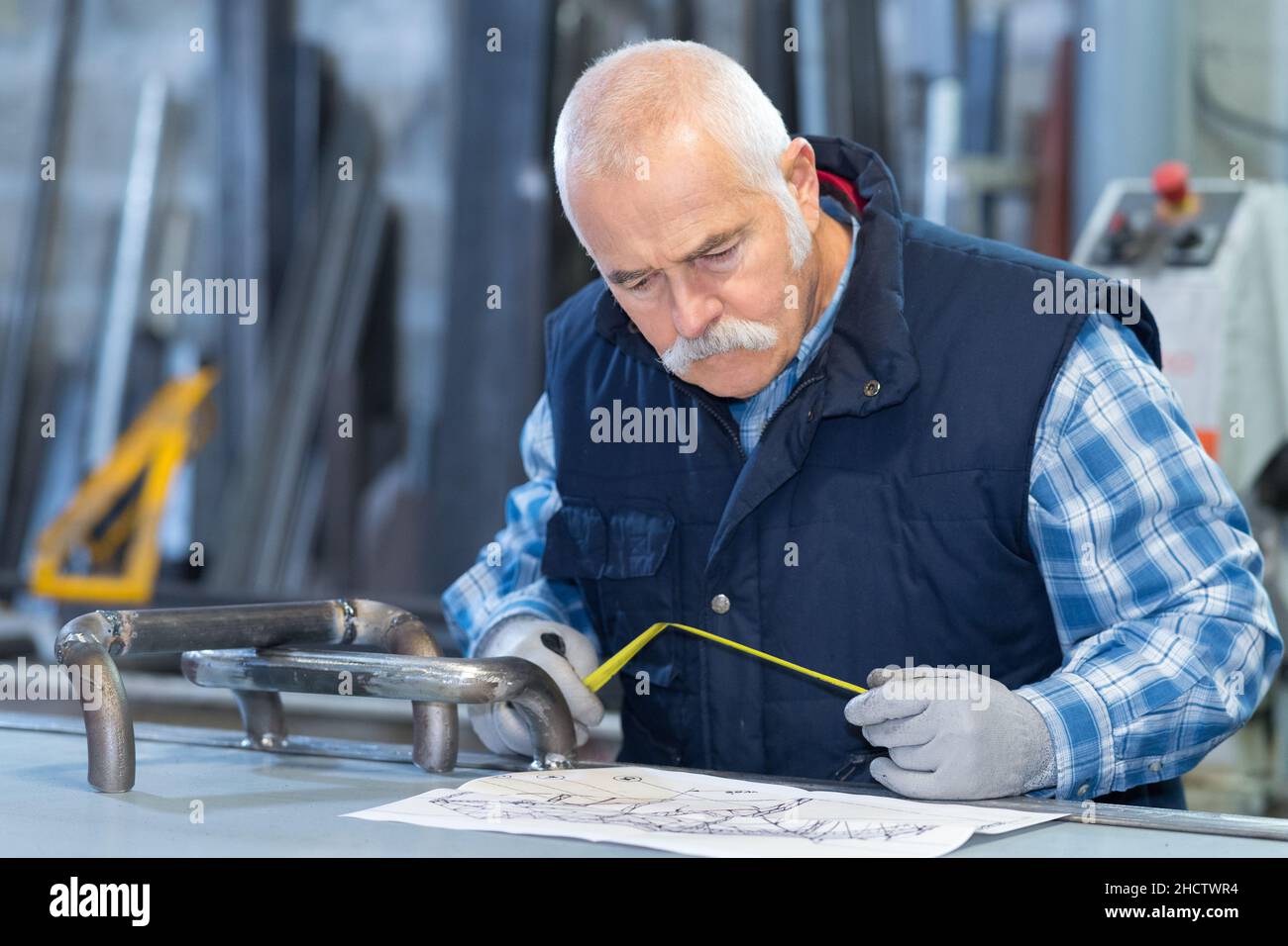 Builders Using Measure builder measuring blueprints with tape measure Stock Photo - Alamy
