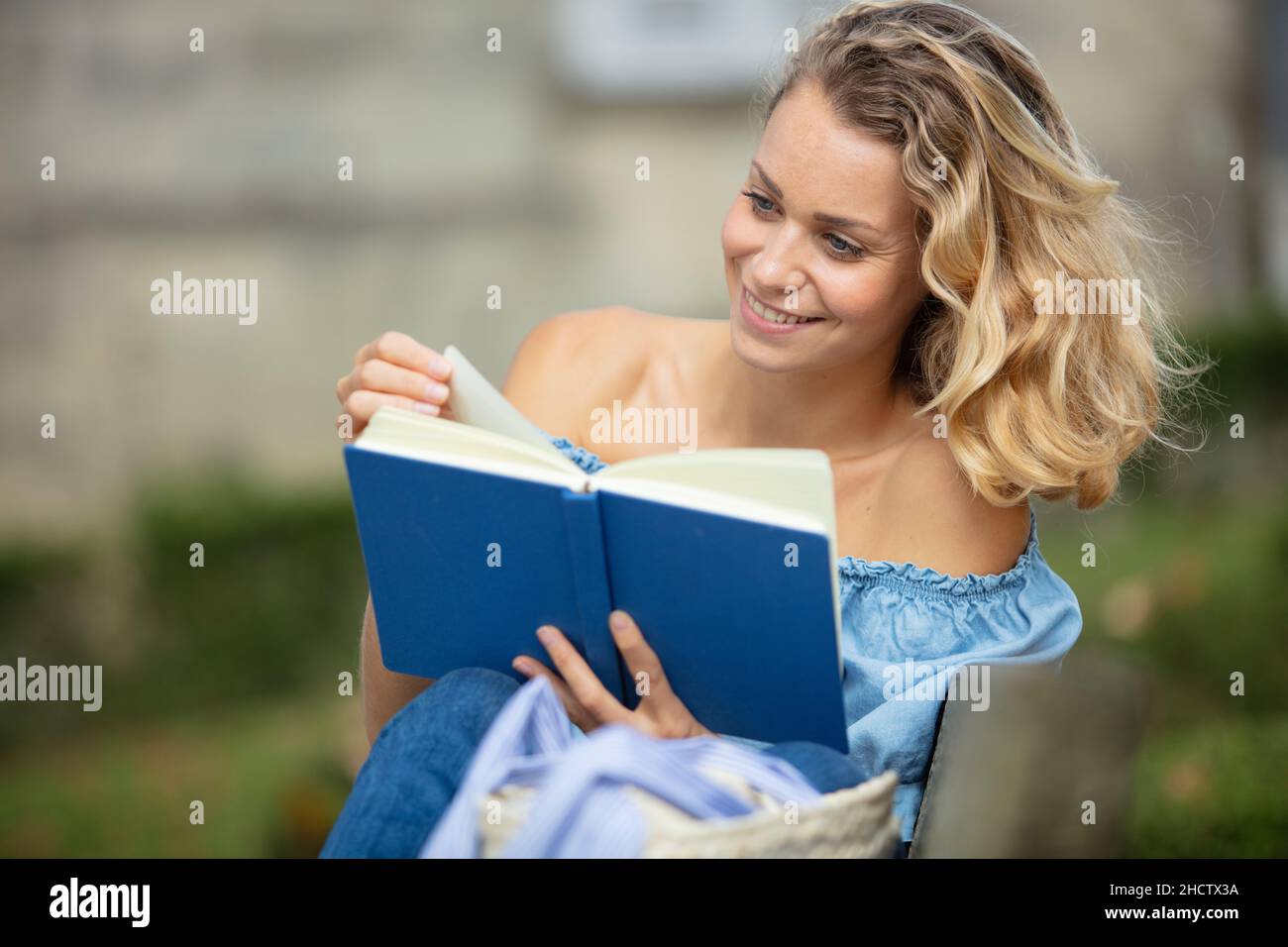 happy blonde girl sitting and reading a book Stock Photo