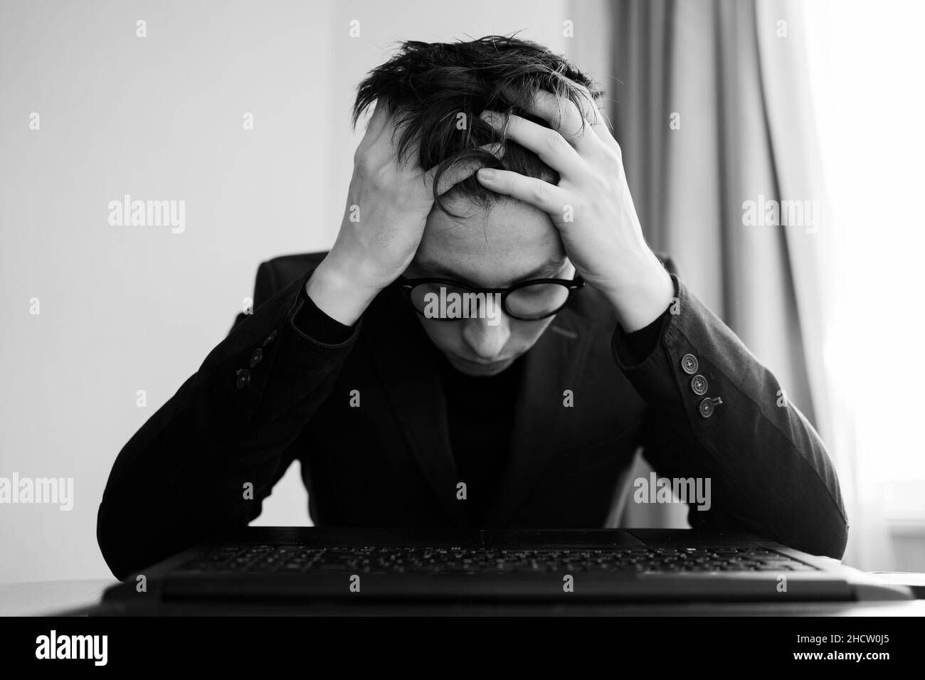 Portrait of stressed business man in office, bad news dismissal from work, man with headache at work, employee migraine, webcam view, black and white Stock Photo