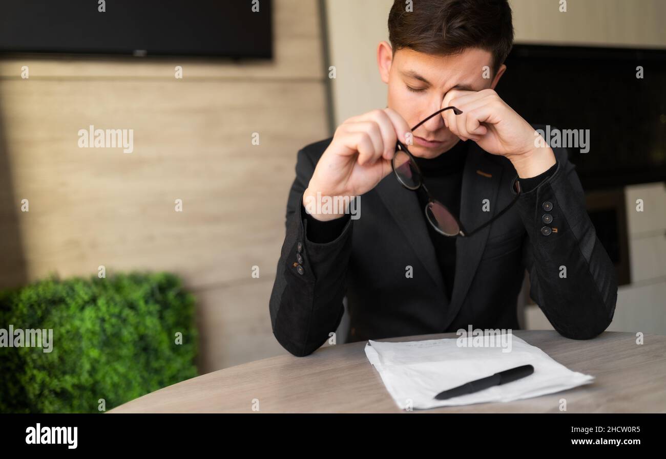 Tired worker takes off glasses, massages eyes, headache and migraine