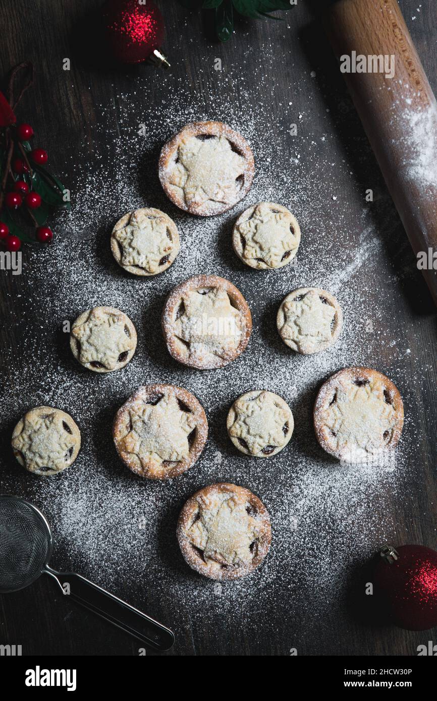 A home baking concept of traditional Christmas mince pies arranged in the shape of a Christmas Tree and covered in icing sugar Stock Photo