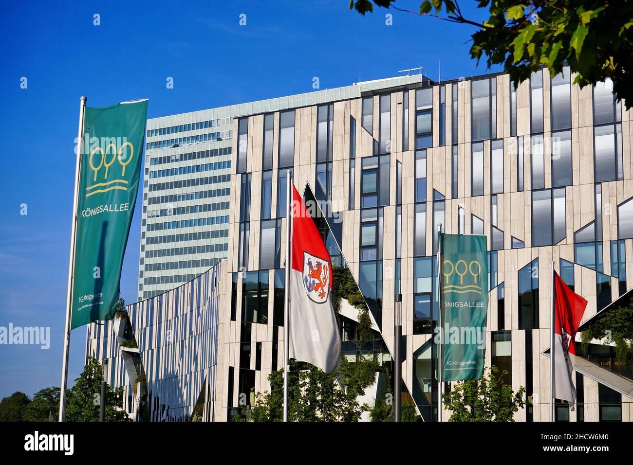 A modern building at Kö-Bogen in Düsseldorf, designed by New York star architect Daniel Libeskind, with Düsseldorf and Königsallee flags in front. Stock Photo