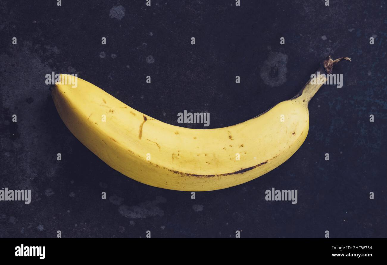 Ripe yellow bananas fruits, bunch of ripe bananas with dark spots on a dark background Stock Photo