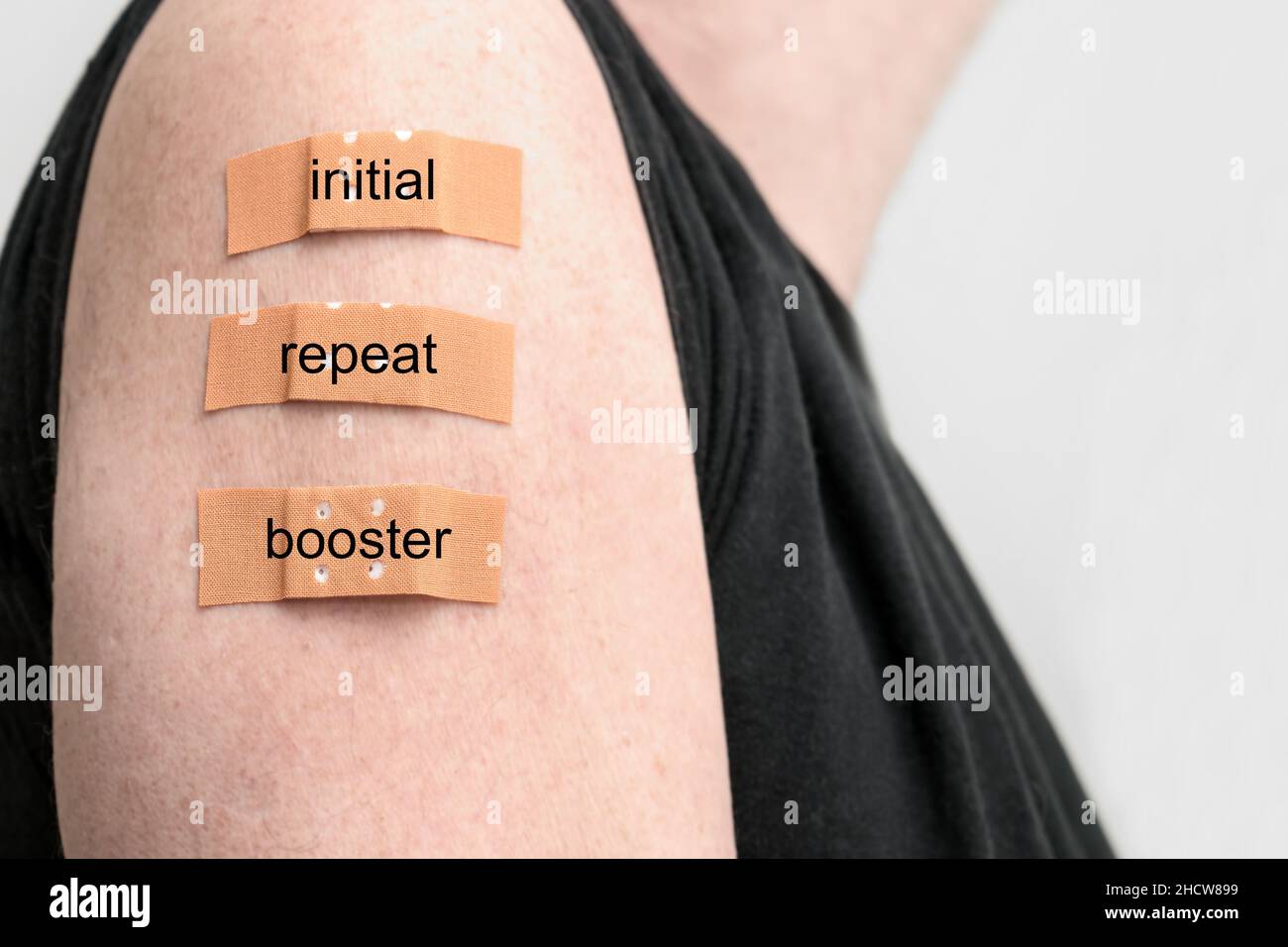 Male arm with three medical plasters after vaccinations against covid-19, text - initial, repeat and booster dose, copy space, selected focus, narrow Stock Photo