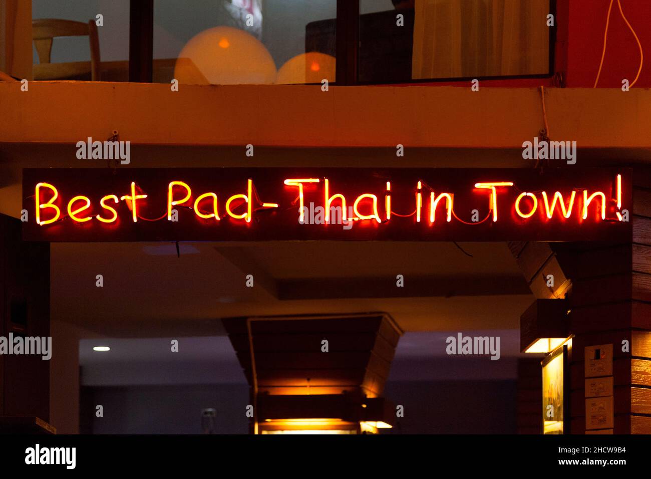 Red neon light above a restaurant saying Best Pad-Thai in town!. Stock Photo