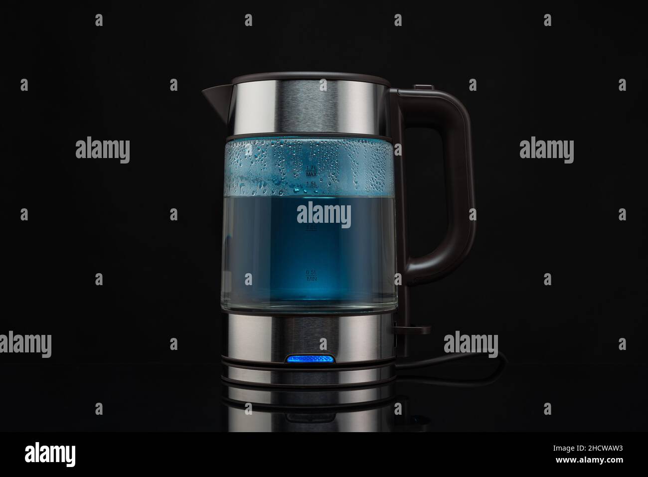 Electric glass kettle for boiling water for hot drinks on a black