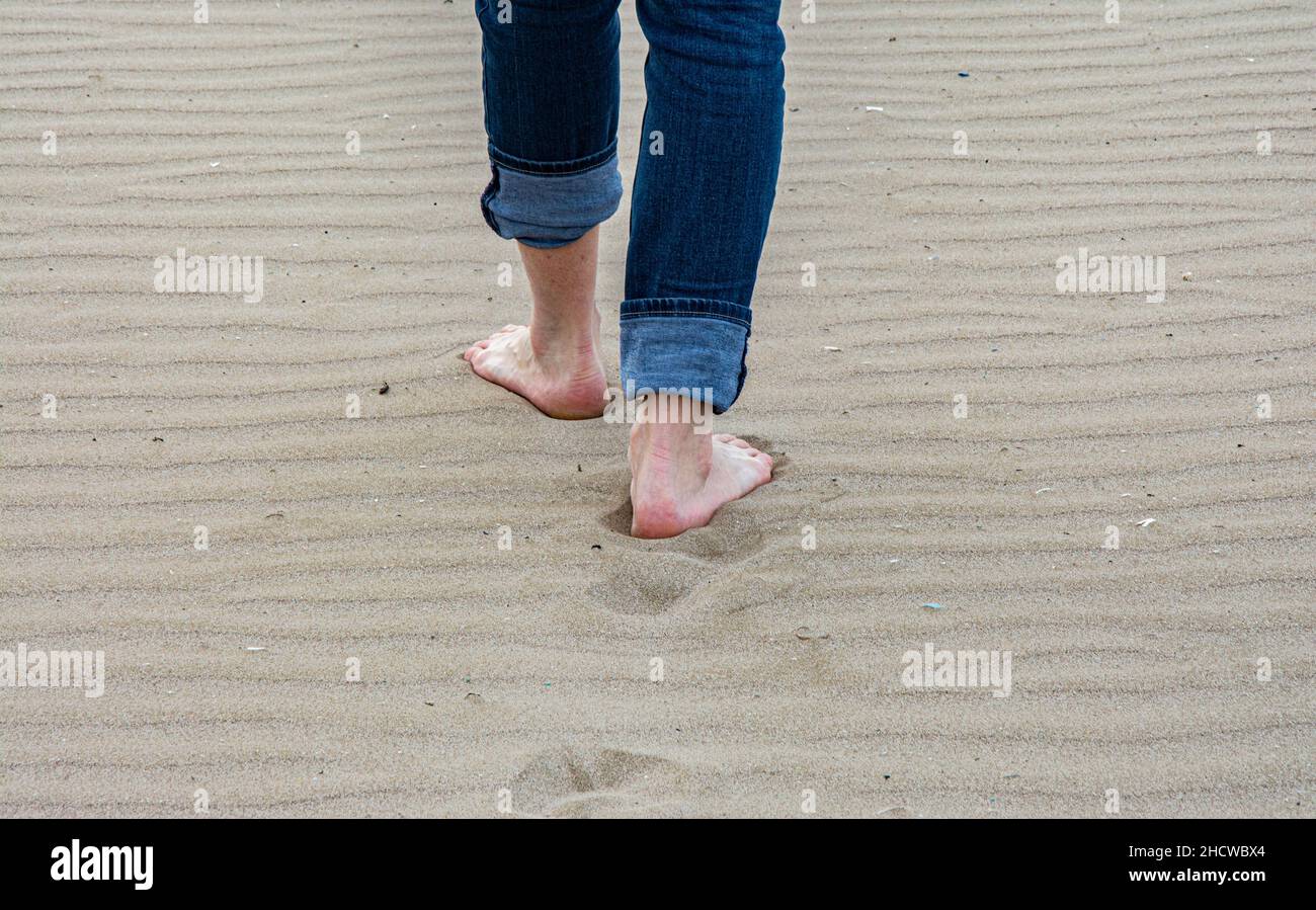 Woman walking on sandy beach leaving footprints in the beach Stock ...