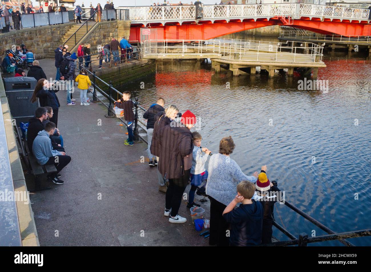 Families crab fishing in Whitby harbour, north Yorkshire Stock Photo