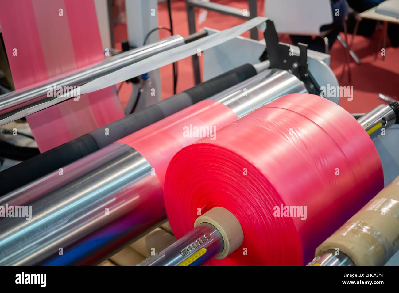 Automatic plastic bag making machine: moving roller with pink film at trade show Stock Photo