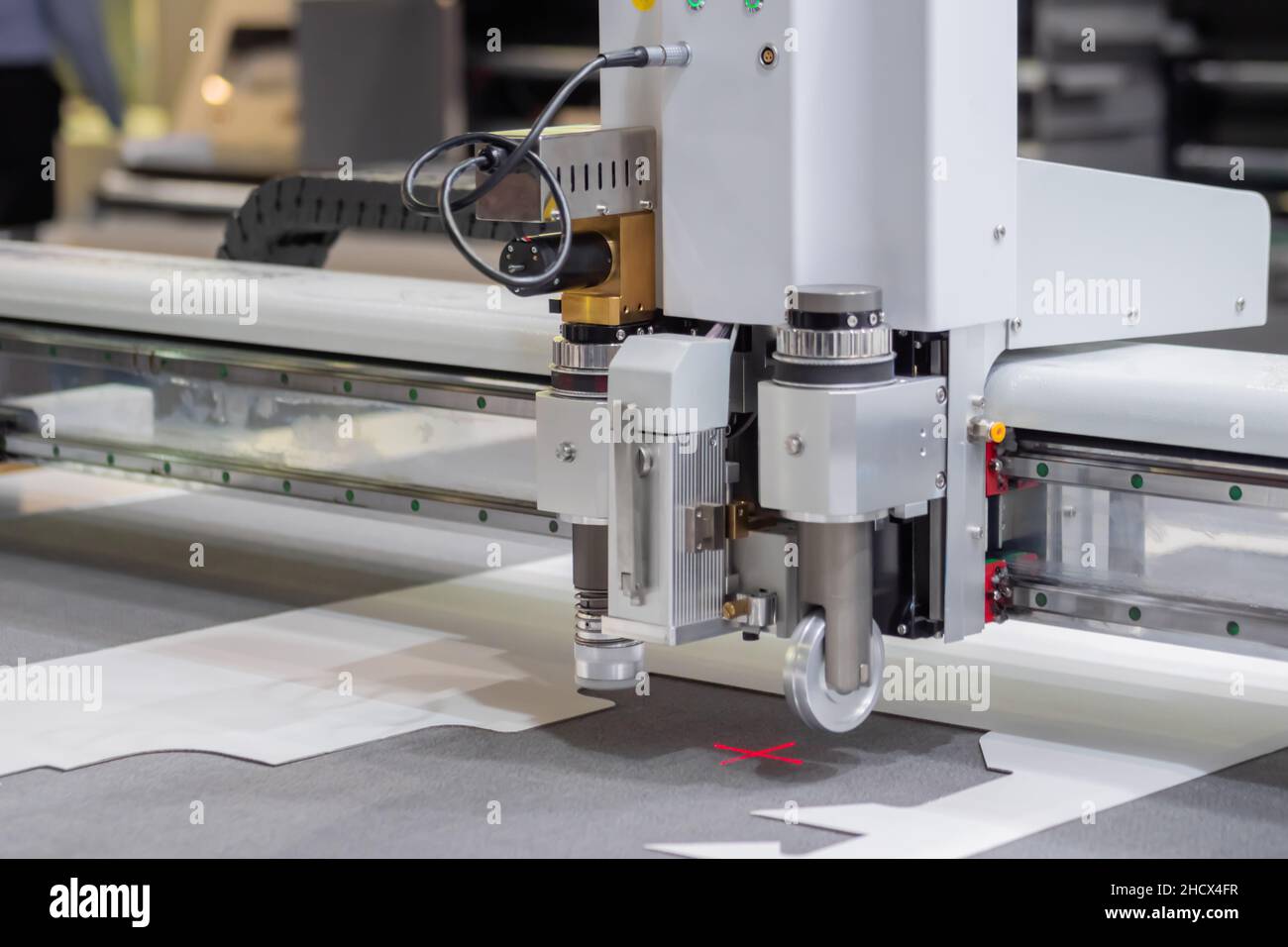 Digital flatbed cutter, plotter cutting white cardboard sheet at exhibition Stock Photo