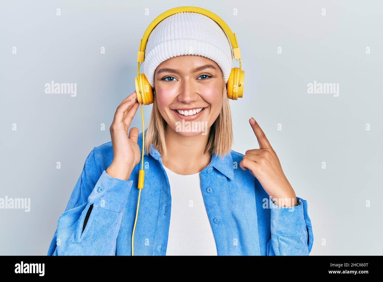 Beautiful blonde woman listening to music using headphones smiling ...