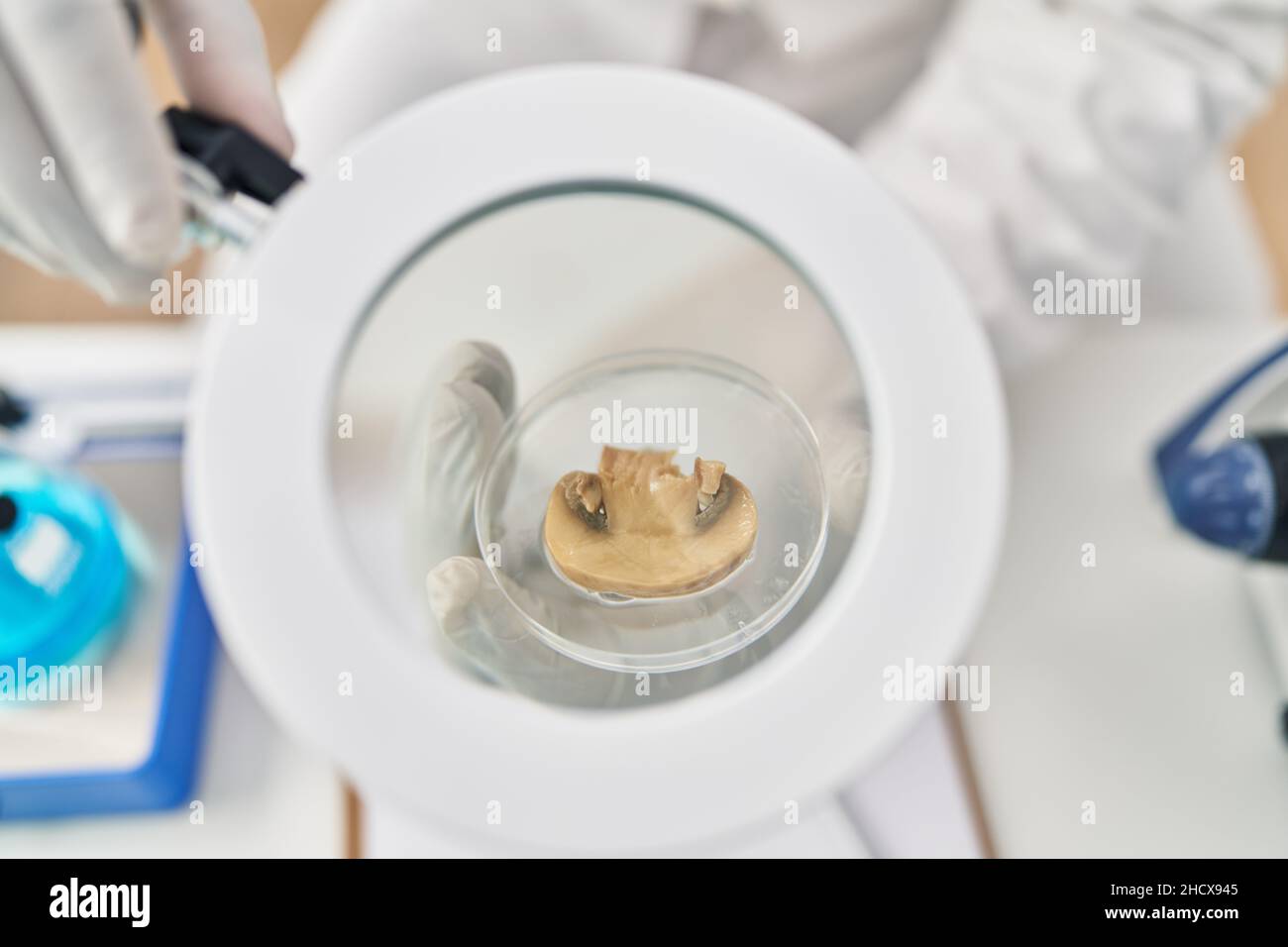 Young african american man wearing scientist uniform using loupe at