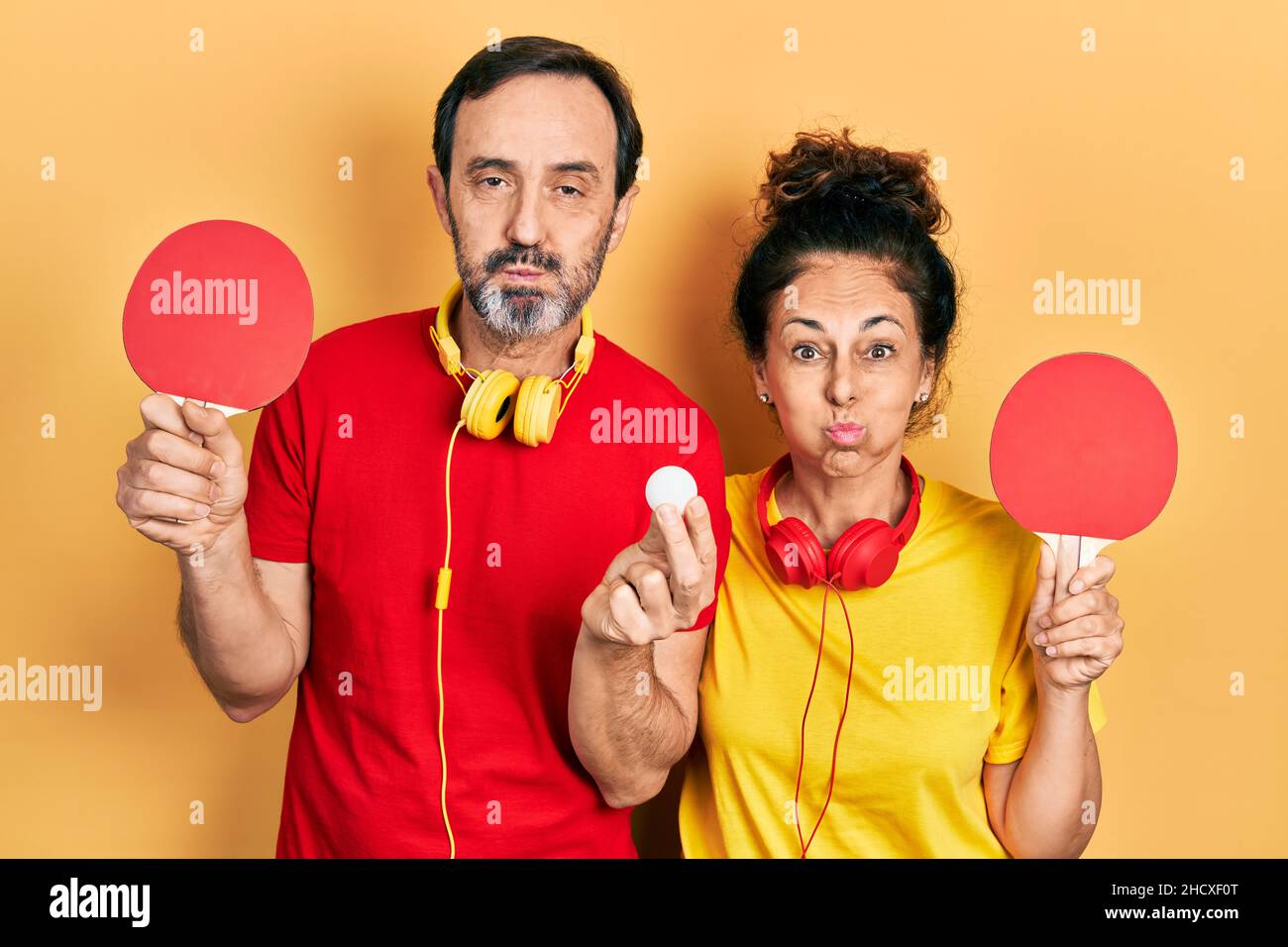 Weird Ping Pong Rackets Middle age couple of hispanic woman and man holding red ping pong ...