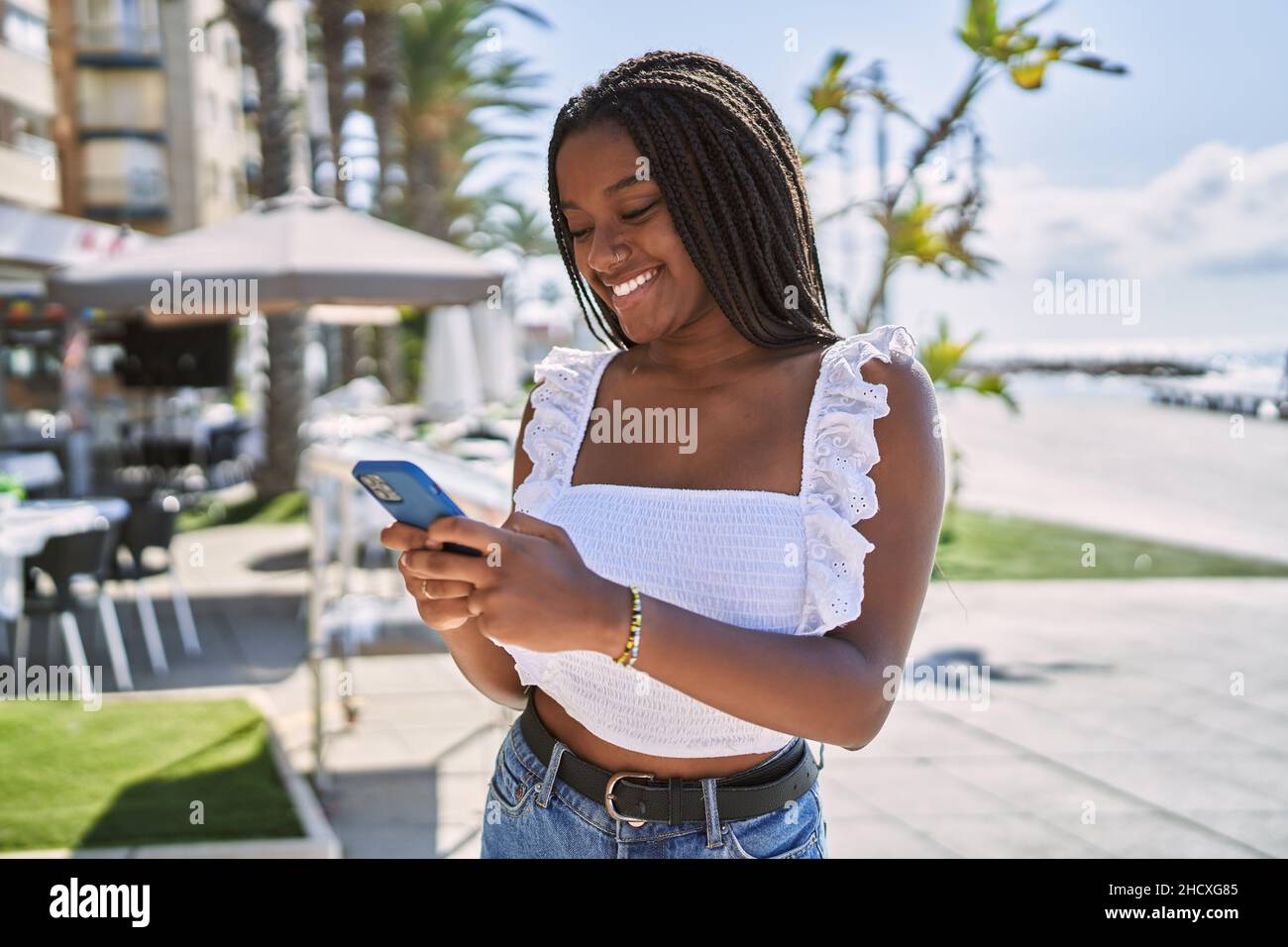 Young african american girl smiling happy using smartphone at the ...