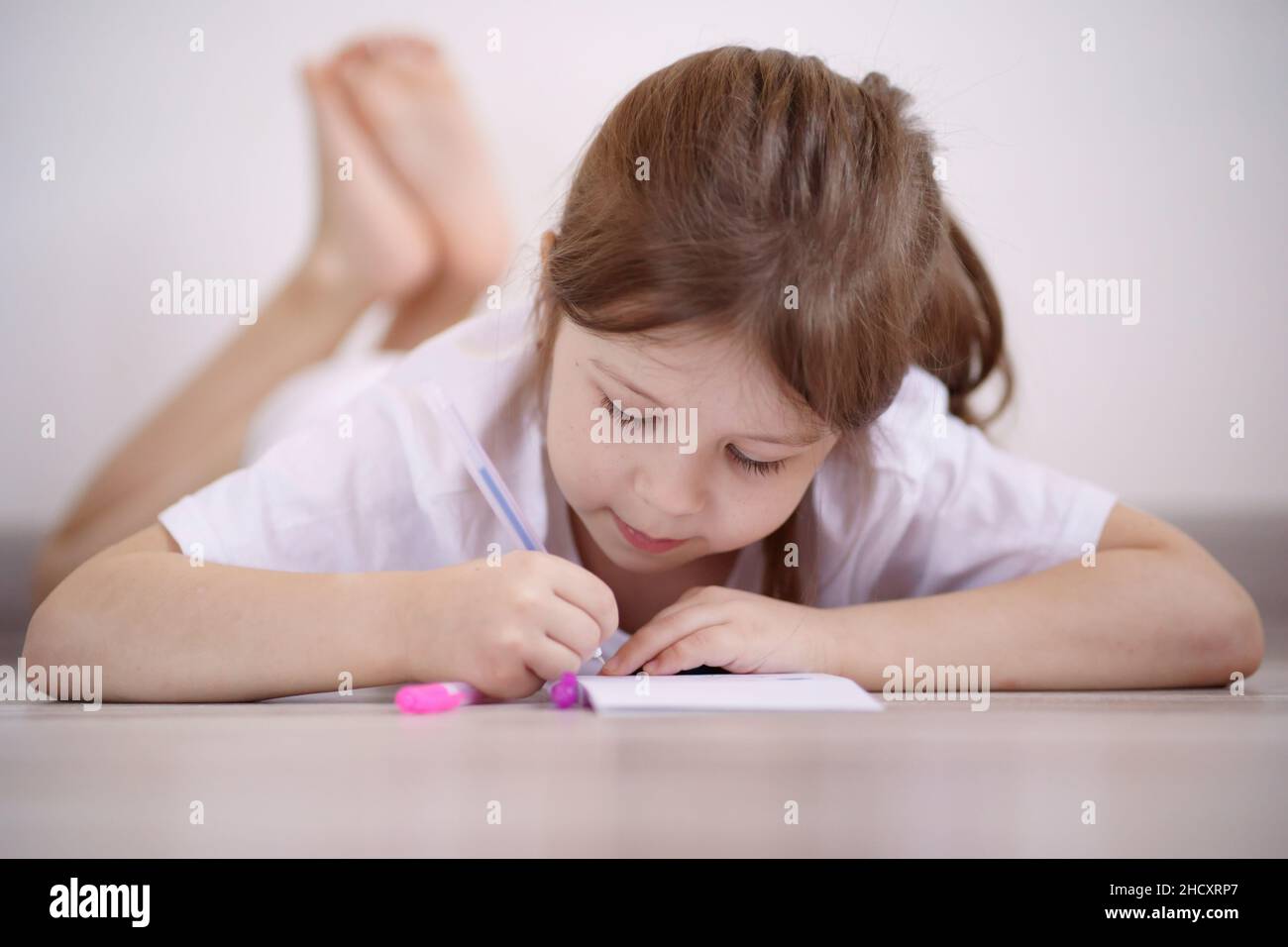 Little girl lies on the floor and draws Stock Photo - Alamy