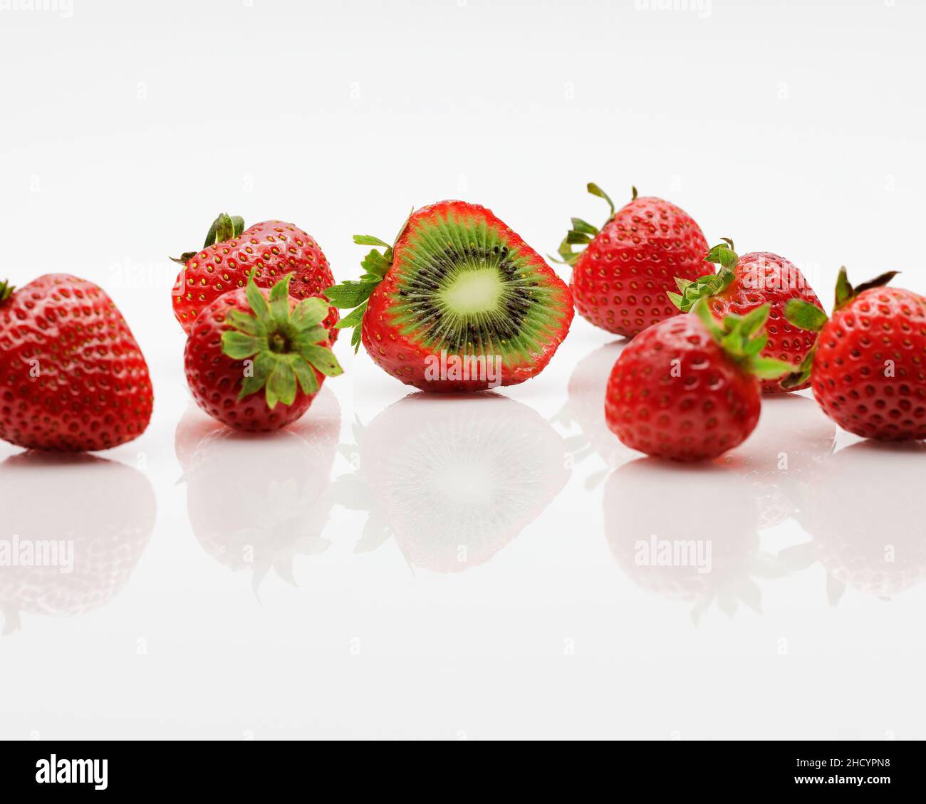 A hybrid fruit of strawberries and kiwi fruit, cut open to expose the unusual flesh of the fruit. Stock Photo