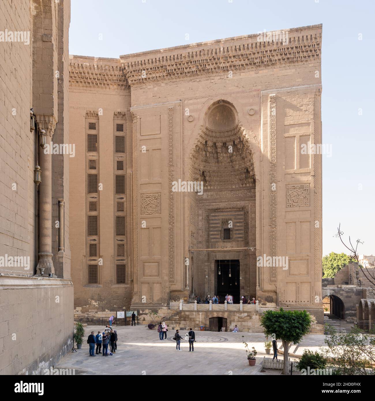 Cairo, Egypt - November 27 2021: Facade of Islamic Mamluk era Mosque and Madrassa of Sultan Hassan, with side facade of royal era Al Rifai Mosque, with few visitors, Old Cairo Stock Photo