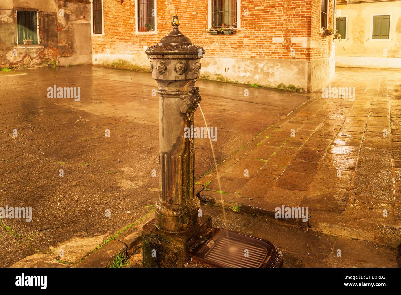 ancient drinking fountain in Venice on city square by rainy night Stock Photo