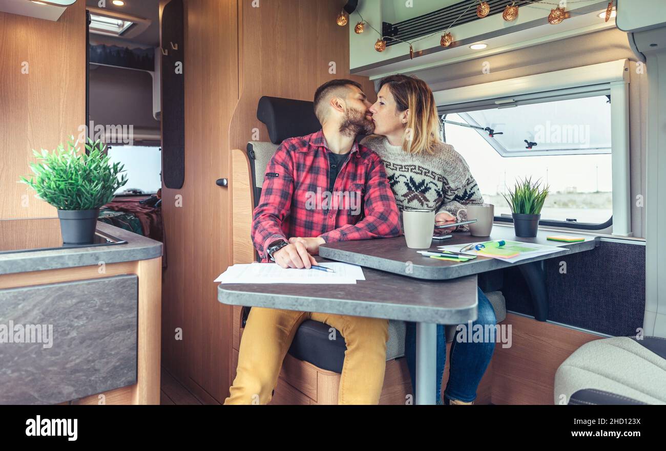 Couple kissing while telecommuting in a camper van Stock Photo - Alamy