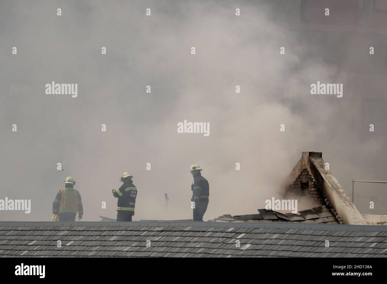 Firemen work at the parliament where a fire broke out in Cape Town, South Africa, January 2, 2022. REUTERS/Mike Hutchings Stock Photo