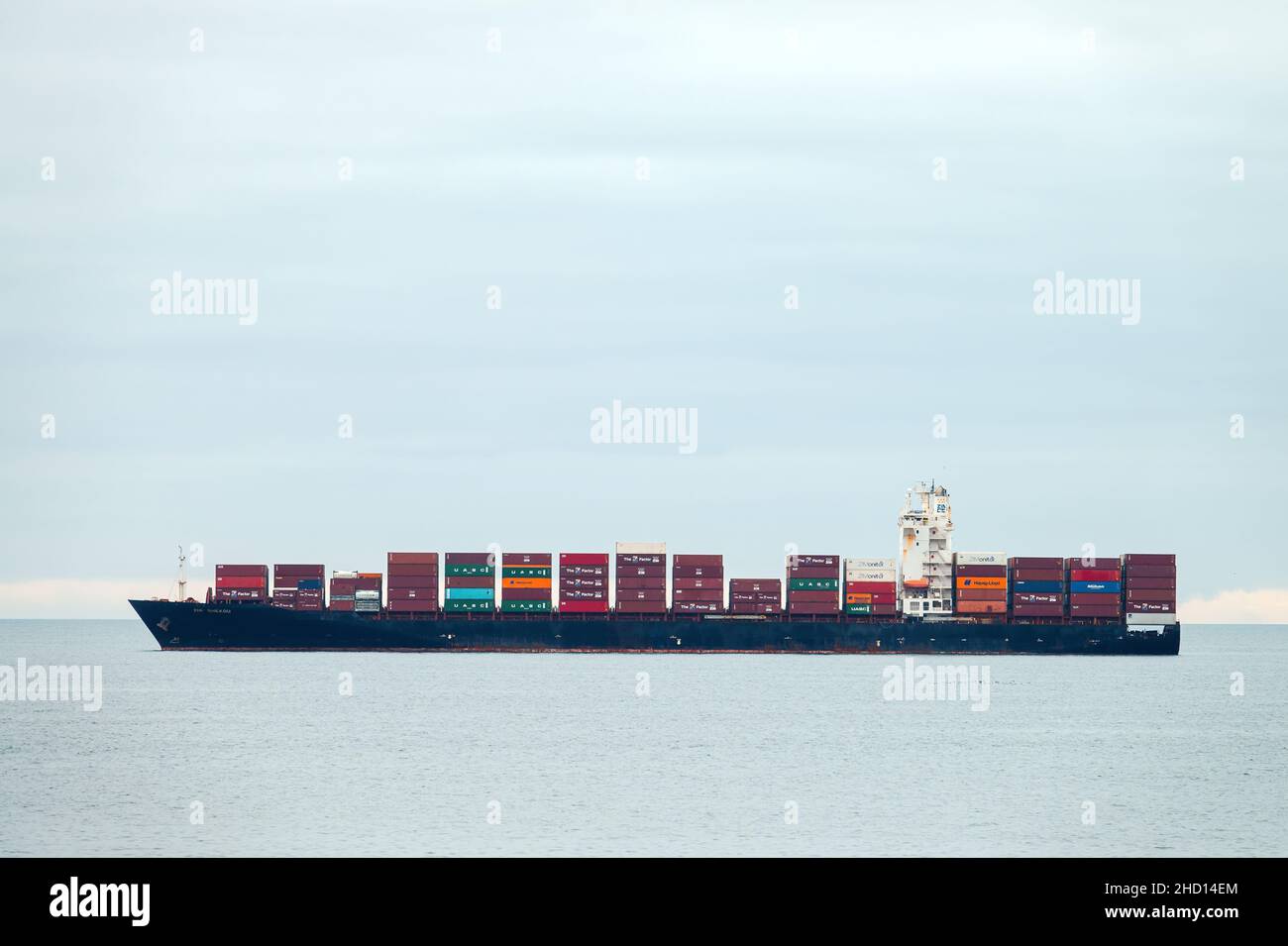 Container cargo ship, profile view, transport of shipping goods. Genova Italy - December 2021 Stock Photo