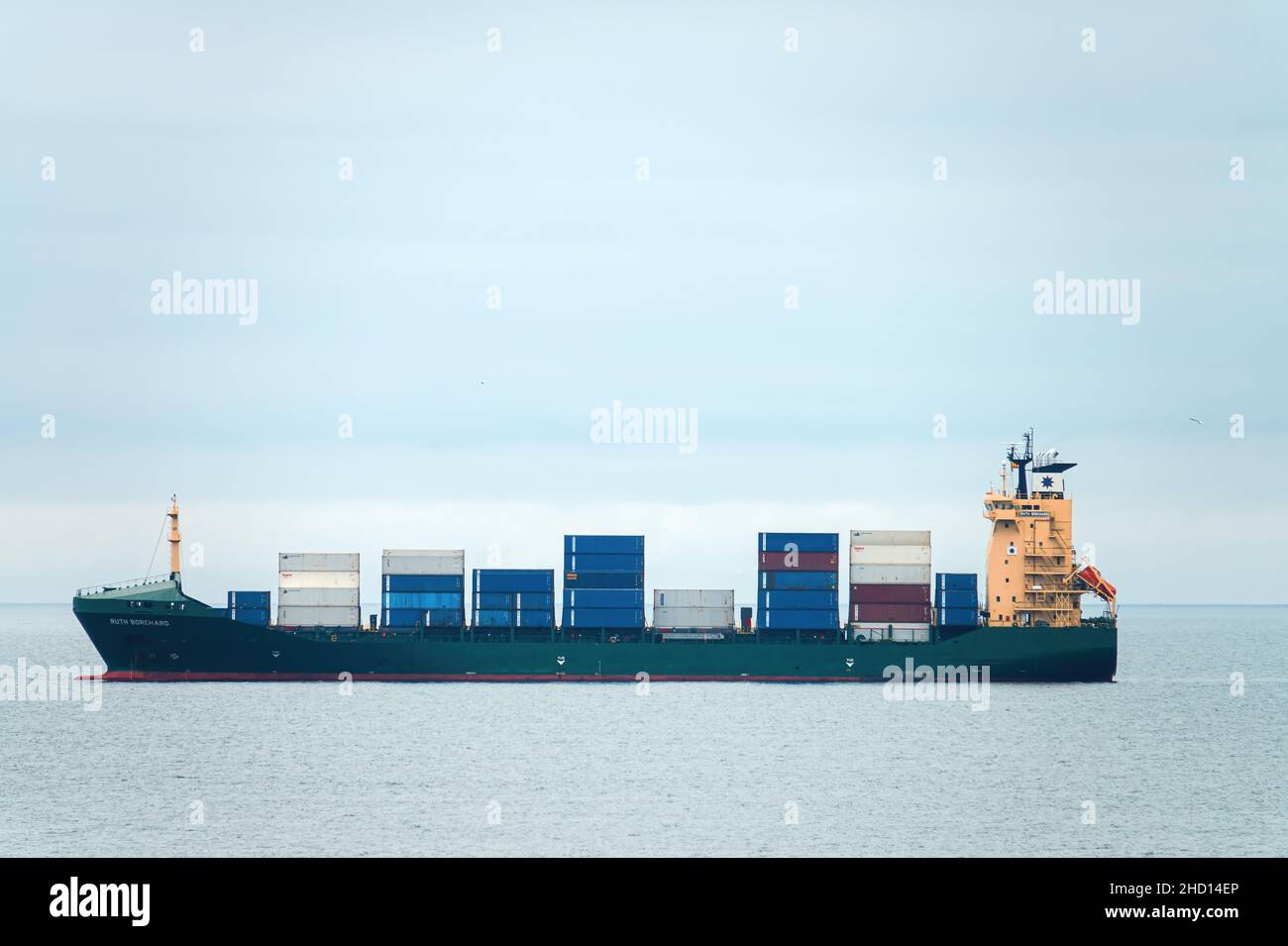 Container cargo ship, profile view, transport of shipping goods. Genova Italy - December 2021 Stock Photo