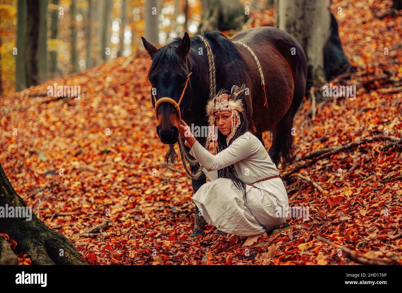 Shaman woman in autumn landscape with her horse. Stock Photo