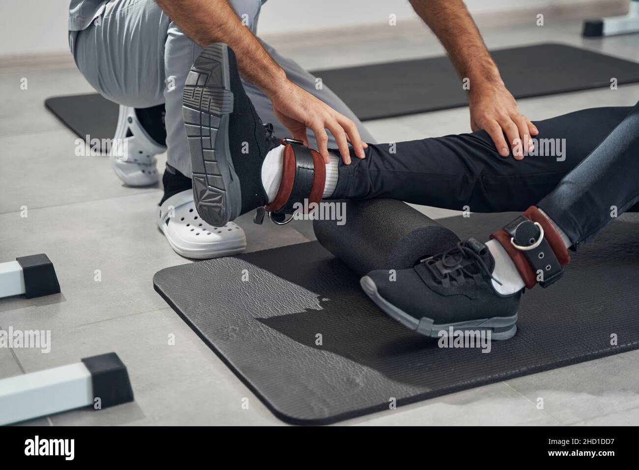 Patient foamrolling lower leg muscles assisted by physiatrist Stock